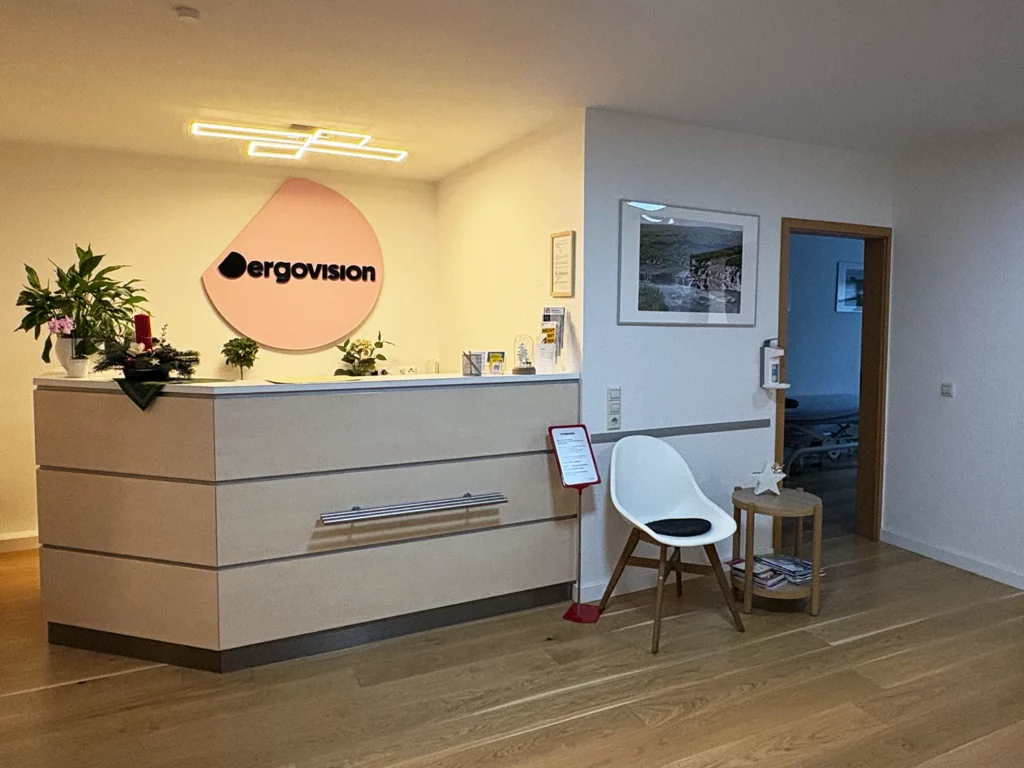 Empfangsbereich der Ergotherapie-Praxis ergovision in Leipzig mit Rezeption, Logo und Sitzgelegenheit